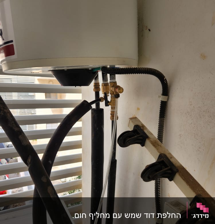 דוד שמש עם צינורות ומחברים על קיר חיצוני